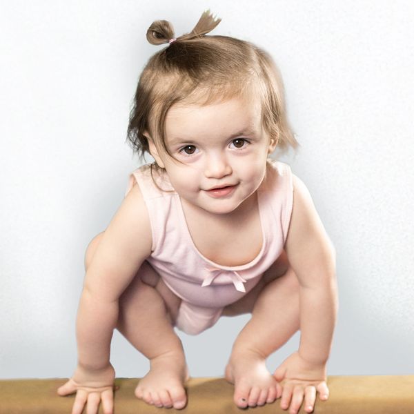 Cute baby girl squatting and looking at the camera.
