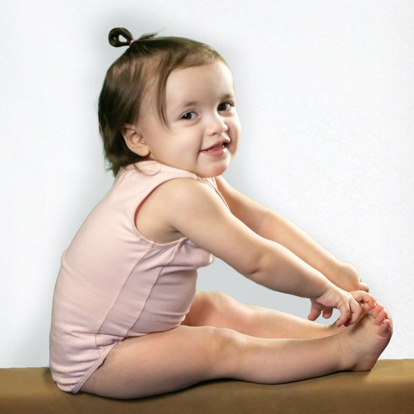 Smiling toddler stretching while sitting.