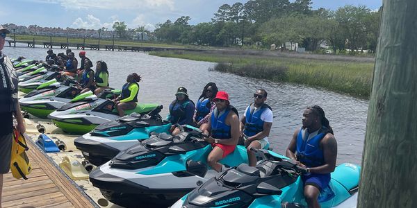 Customers on Jetskis at the dock getting their instructions before they go on the water to have fun.