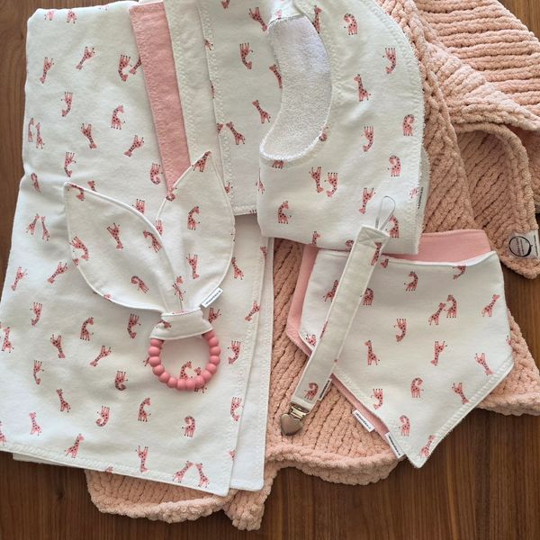 Set of baby accessories with giraffe print and pink accents.