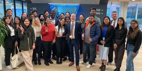 A diverse group of people posing happily indoors for a group photo.