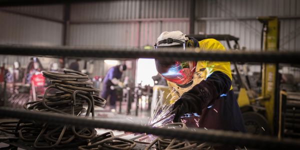 Worker welding metal in a workshop with sparks flying.