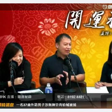 Three hosts discussing on a live radio show with microphones and notes.