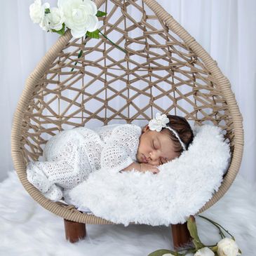 Sleeping baby in a wicker cradle with white flowers.