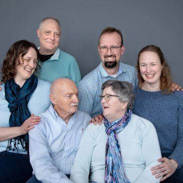 Group of six smiling adults posing in a studio. Family session.