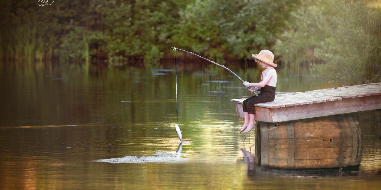 Child fishing on a wooden dock with a fish caught.