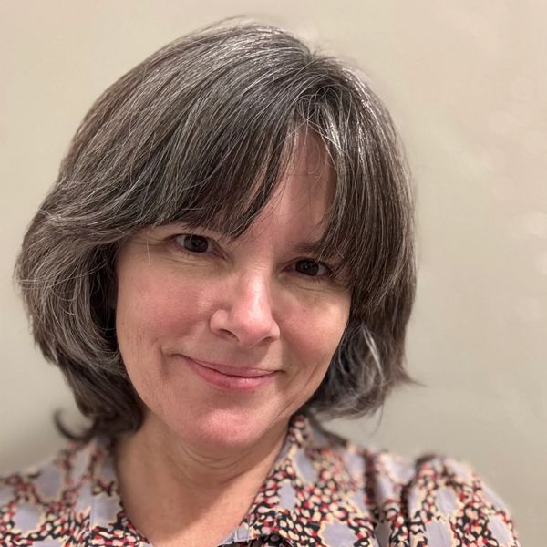 Smiling woman with gray hair and patterned blouse.