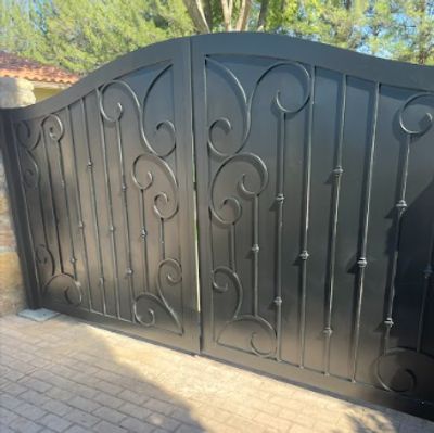 Black wrought iron gate with decorative scrollwork and vertical bars.