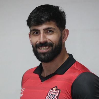 Smiling man with beard wearing a red and black sports jersey.