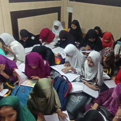 Group of girls in hijabs studying together with books and notebooks.