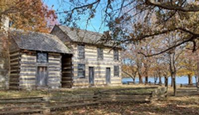 Historic log cabin surrounded by autumn trees.