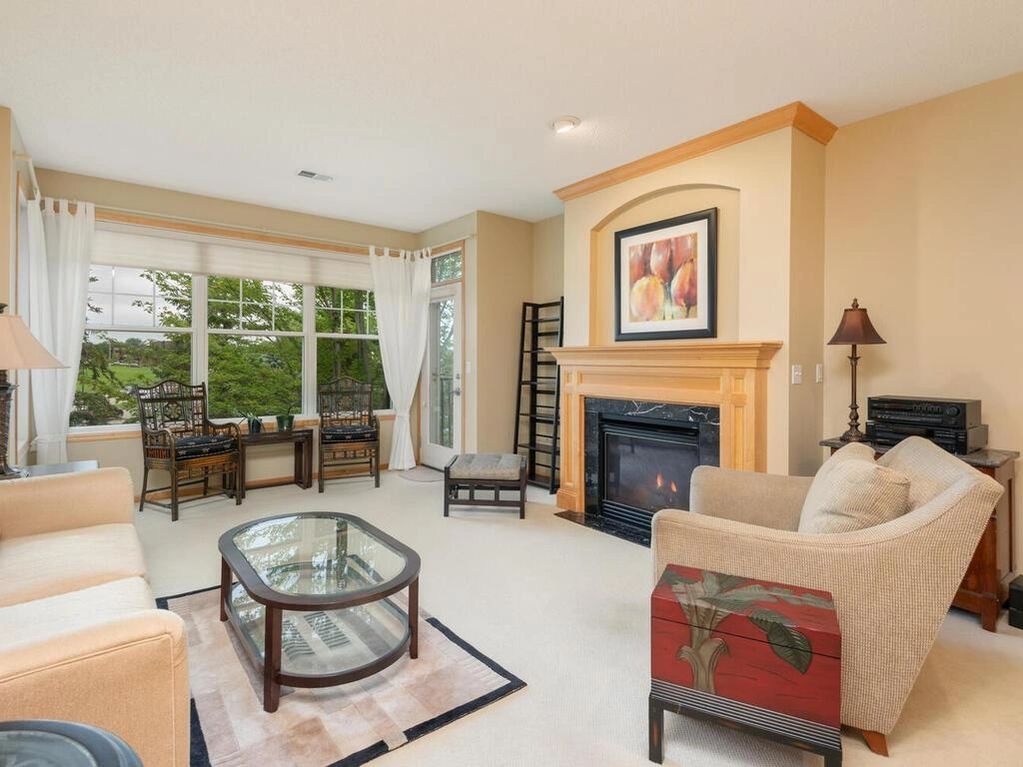 Bright living room with fireplace, glass coffee table, and large windows.