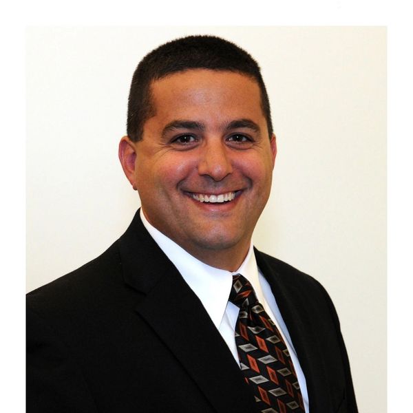 Smiling man in a suit and patterned tie.