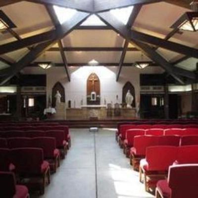 Interior of a church with wooden beams and red pews.