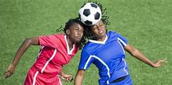 Two female soccer players heading the ball during a match.