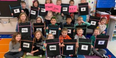 Children holding signs saying 'Thank you MET!'.