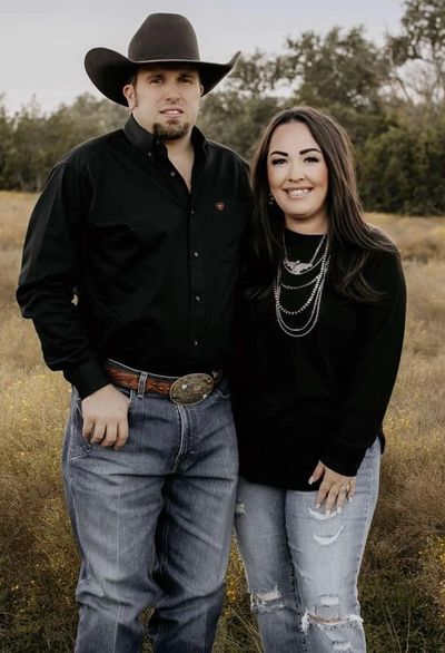 A couple posing outdoors in casual western attire