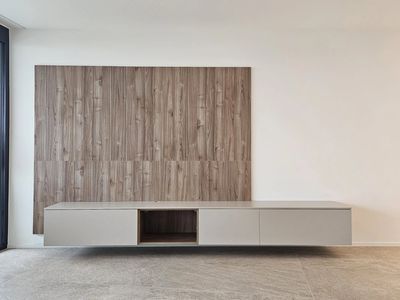 Minimalist wall-mounted cabinet with wood panel backdrop in a modern room.