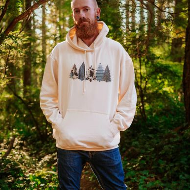 Guy with a beard wearing a cream colored hoodie with trees