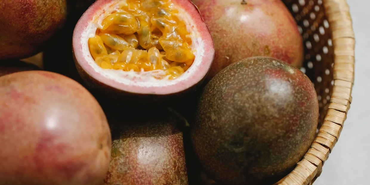 Fresh purple passion fruit cut open in a bowl so the seeds and pulp are visible. 