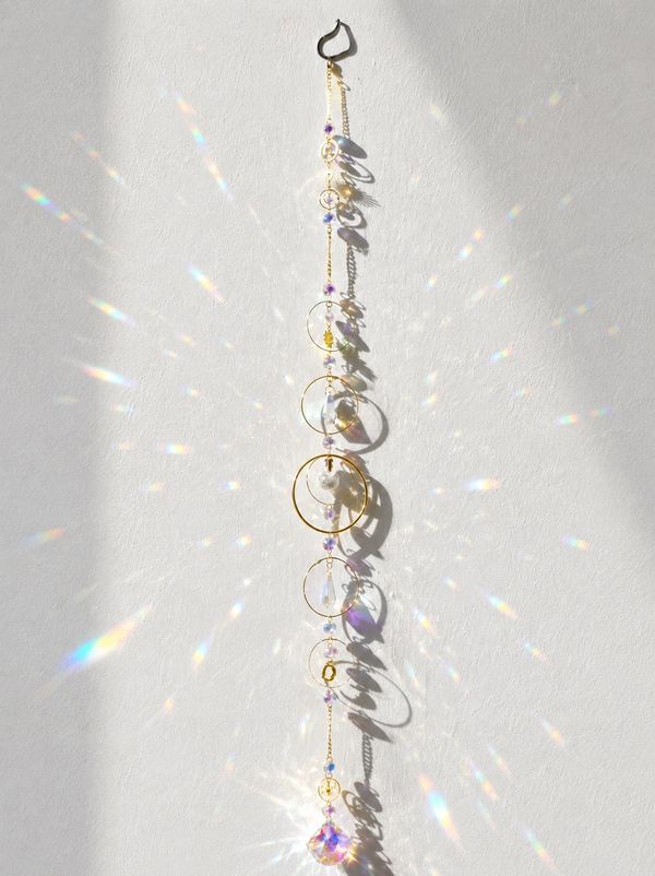 Elegant hanging ornament casting shimmering rainbow reflections on a white wall.
