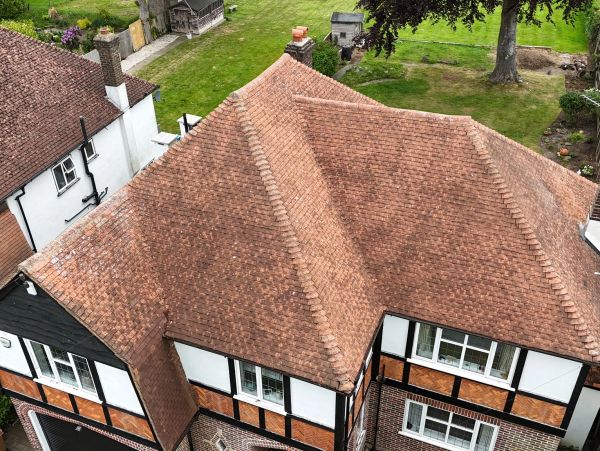 Aerial view of a house with a red tiled roof and white walls with brown accents.