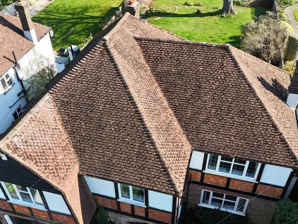 Aerial view of brown-tiled roofs on suburban houses with green lawns.