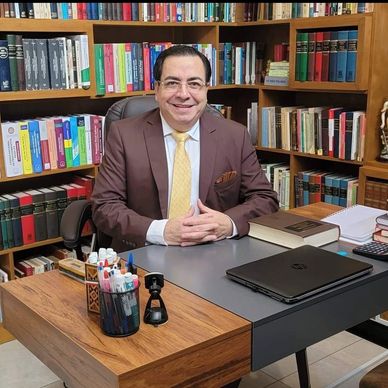 Hombre sonriente en oficina con estanterías llenas de libros.