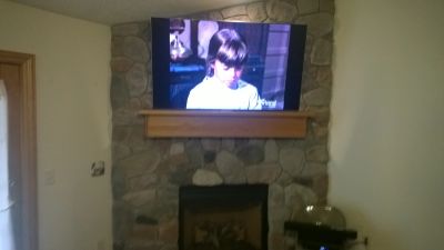 TV mounted on stone fireplace showing a scene with a young girl.