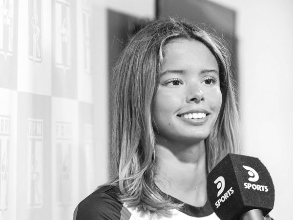 Young woman smiling during a sports interview with a microphone.