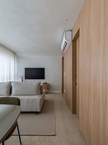 Sala de estar e jantar integradas com sofá em ilha, painel de MDF e ar-condicionado.