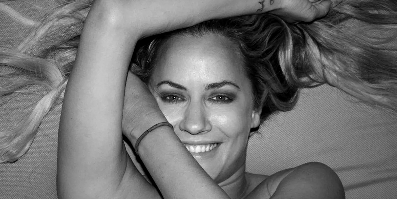 Black and white close-up of a smiling woman lying down.