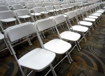Rows of white folding chairs arranged indoors.