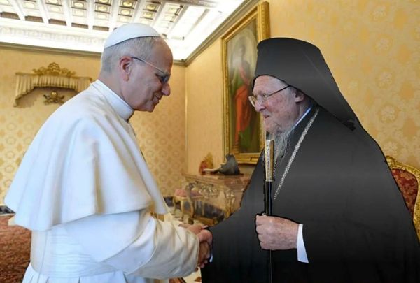 Two religious leaders warmly shaking hands indoors.