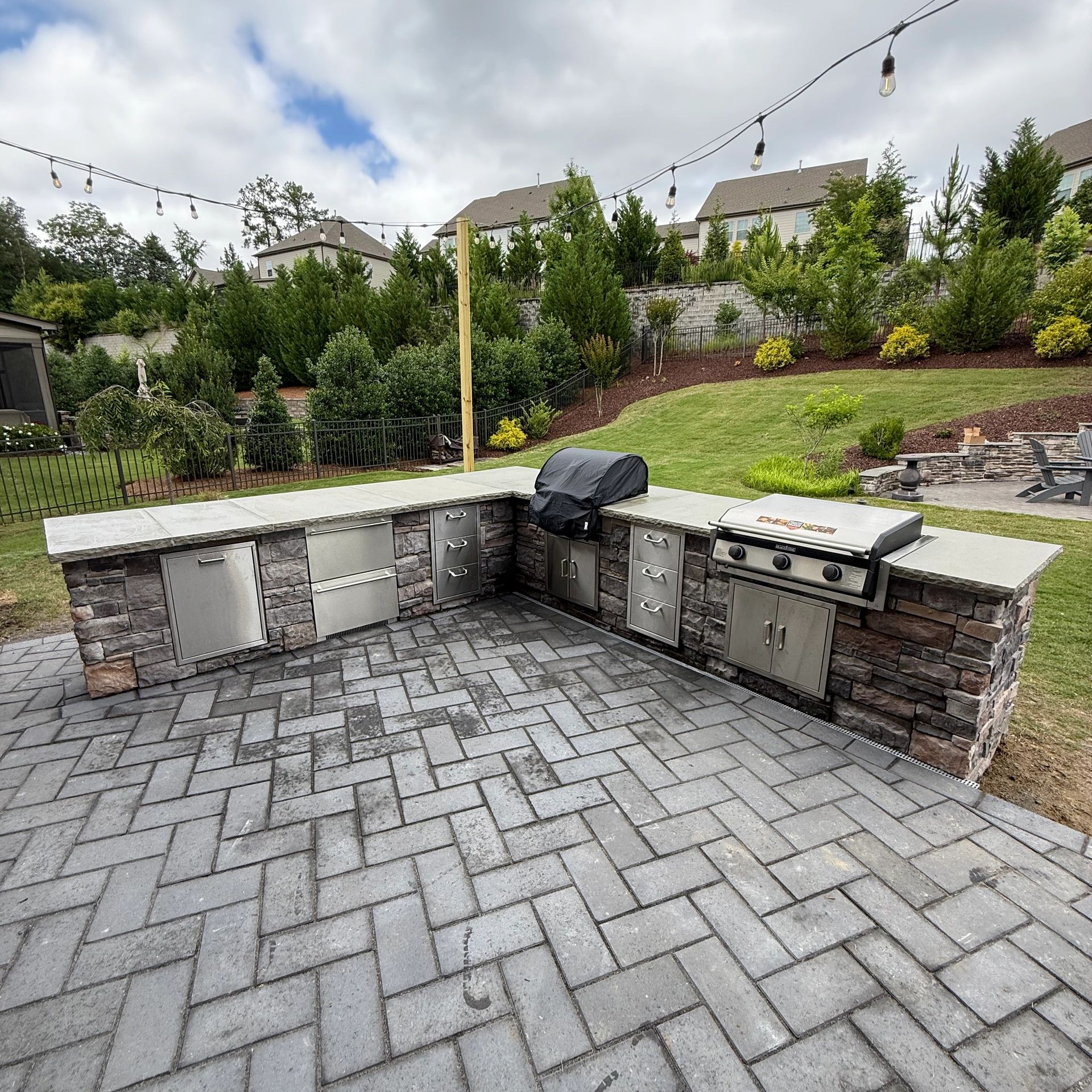 Outdoor kitchen with grill and storage on a patio.