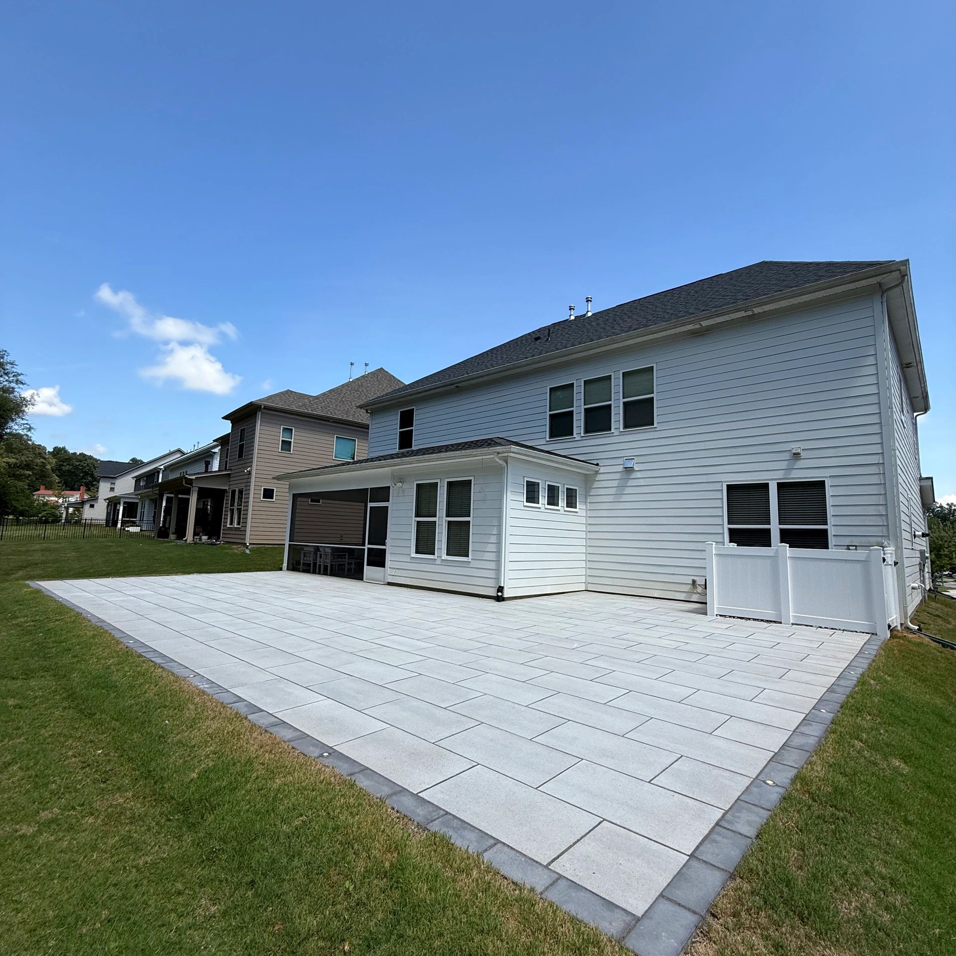 A modern backyard with a tiled patio and two houses.