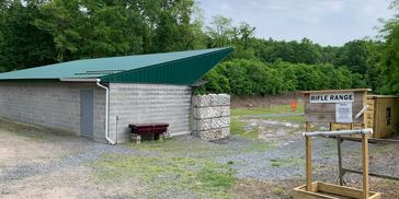 Outdoor rifle range with a shelter and targets in a wooded area.