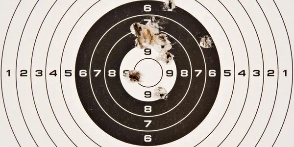 A shooting target with multiple bullet holes near the bullseye.