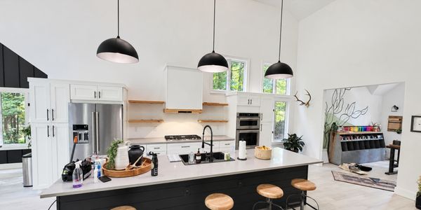 Modern kitchen with island and hanging lights.