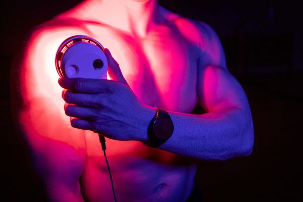 Male athlete using a SunPowerLED Palm handheld device on his shoulder