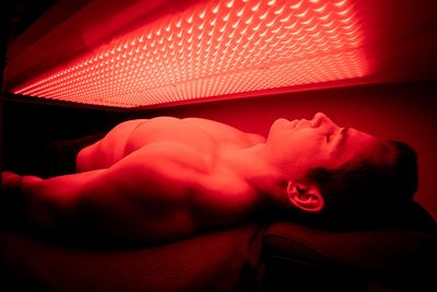 A male model experiences the warmth of the red light therapy under the large SunPowerLED Canopy!