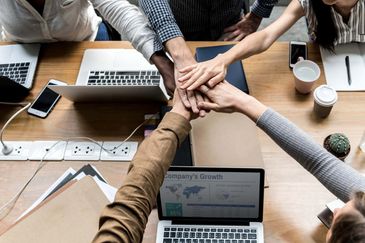Teamwork with hands together over laptops.