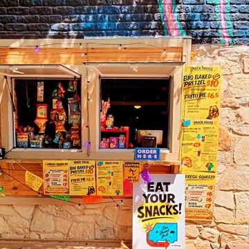 A vibrant snack stand with colorful signs and a variety of snacks on display.