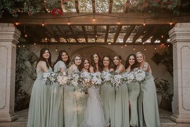 Women in bridesmaid dresses and bride in wedding dress with professional hair and makeup