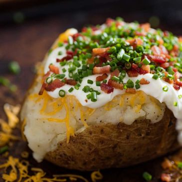 Loaded baked potato topped with sour cream, bacon, chives, and cheese.