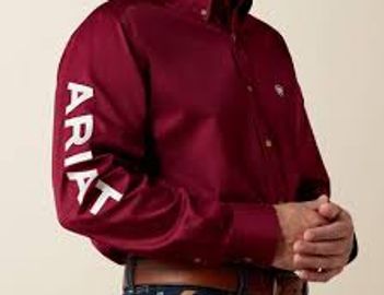 Man wearing a maroon Ariat shirt with the brand name on the sleeve.