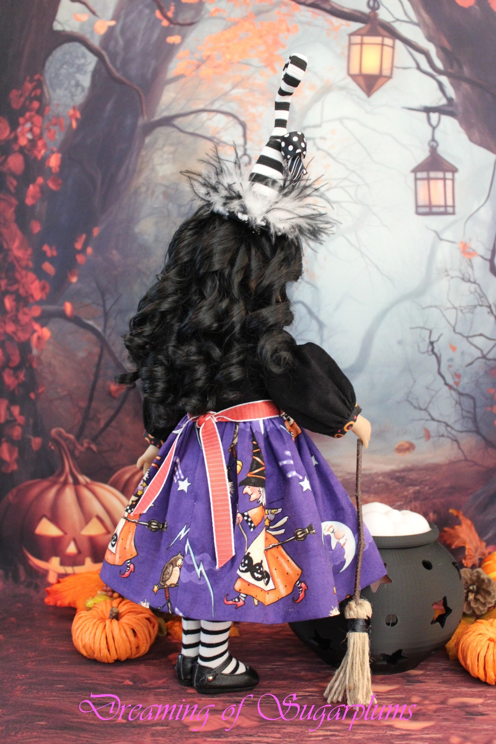 Halloween witch doll with curly hair and striped hat.