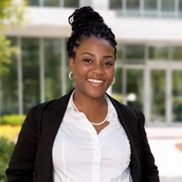 Professional woman smiling outdoors in business attire.