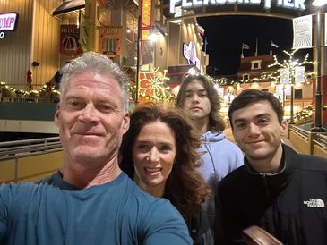 A family selfie taken at night in a festive outdoor setting.