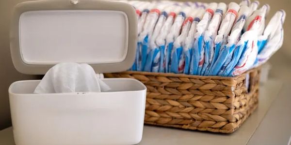 Wipes in a white container and diapers organized in a woven basket.